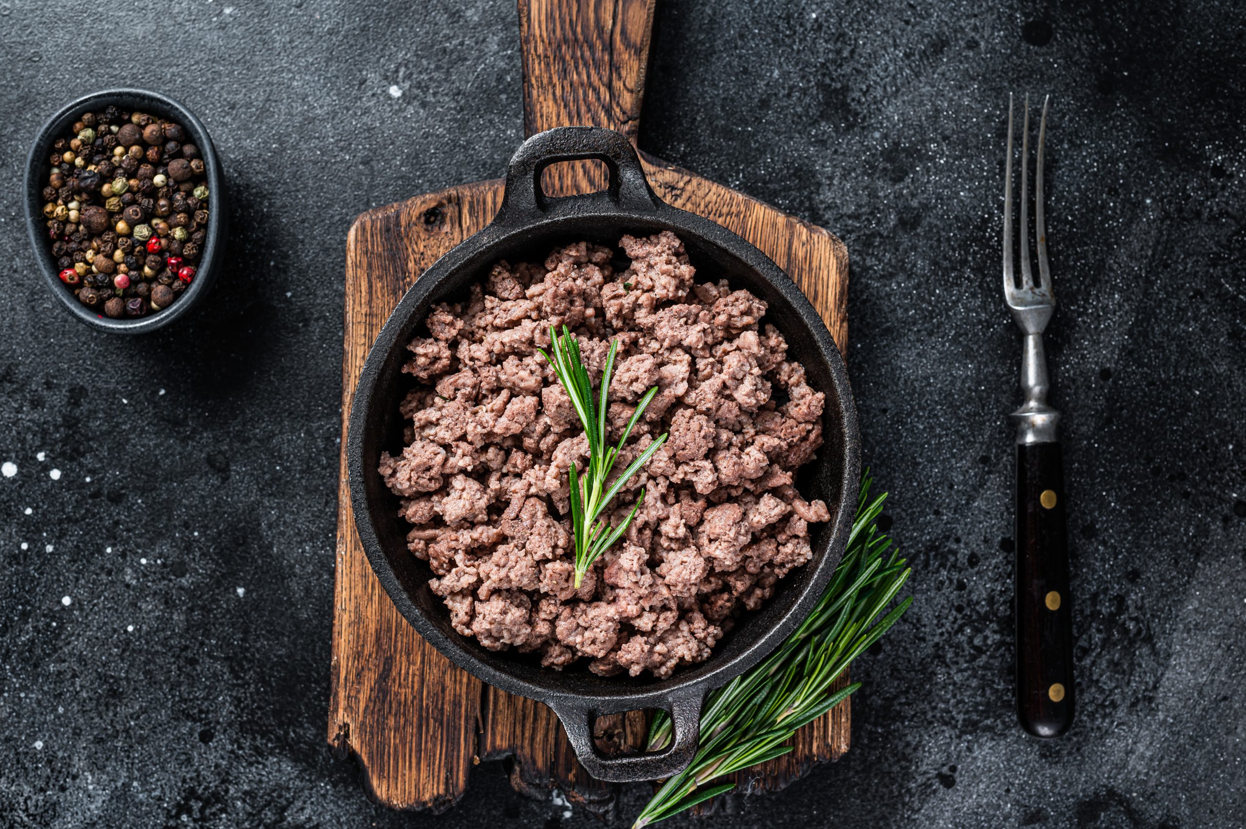 Fried mince beef meat in a pan for cooking pasta. Black background. Top view.